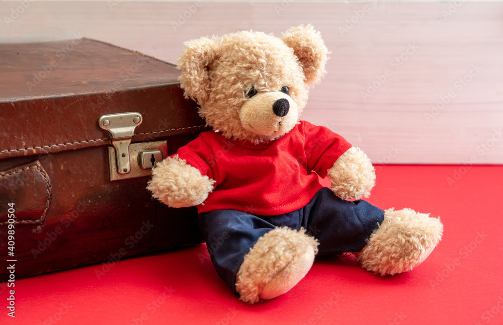 Obraz premium Suitcase and teddy bear on red floor. Retro leather bag in a kid room