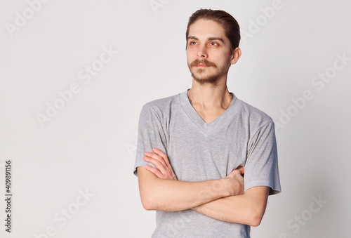 People concept - bearded face man cross arms. Friendly young man in gray shirt look in to the camera over grey background. Copy space