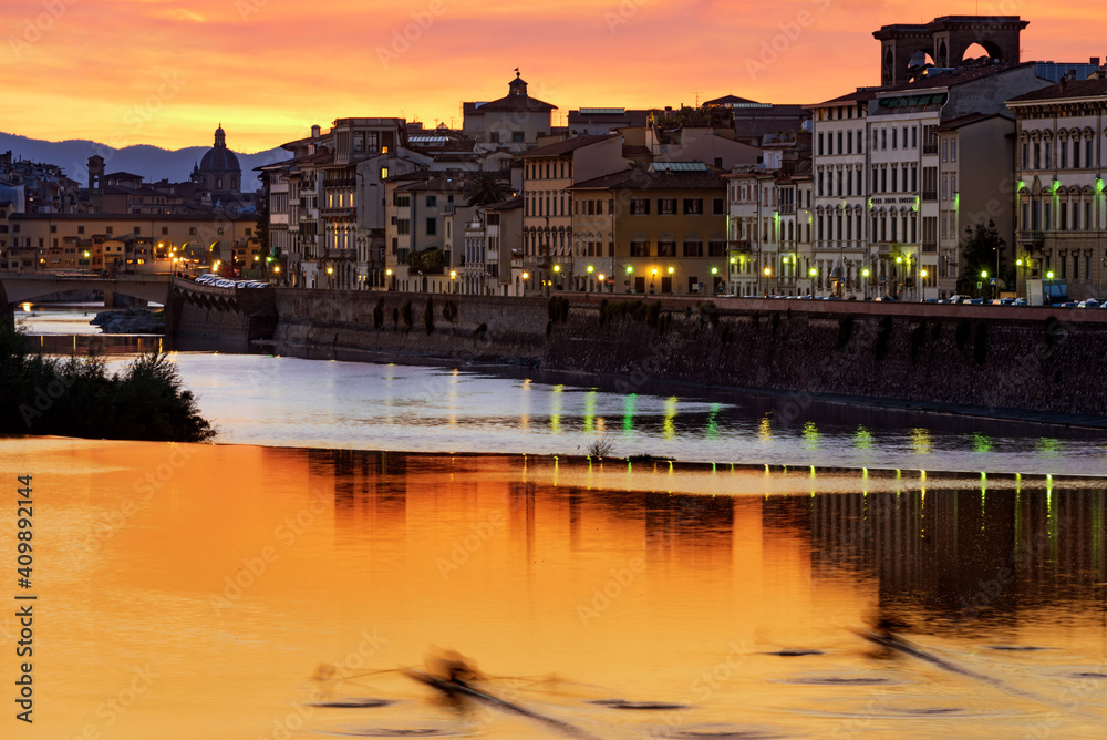 a blurred canoe at sunset on the river arno in florence, italy