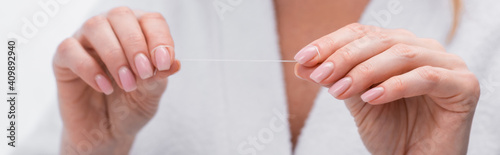 cropped view of woman holding dental floss in hands, banner