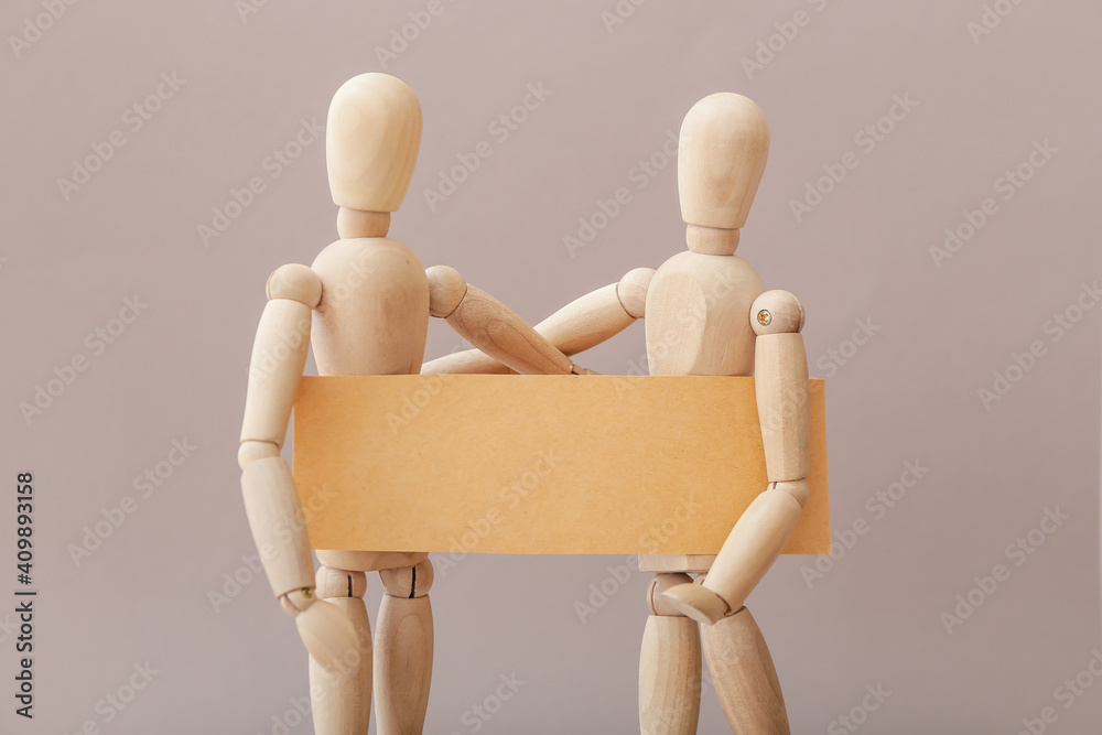 Wooden mannequins with blank poster on grey background Wooden mannequins with blank poster on grey background