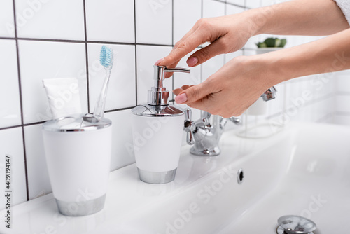 cropped view of woman using soap dispenser in bathroom
