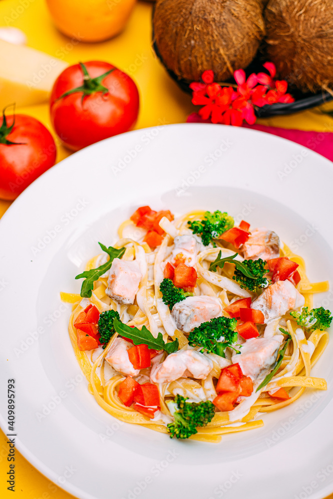 spaghetti with salmon, broccoli and tomatoes in a creamy sauce on a decorated table spaghetti with salmon, broccoli and tomatoes in a creamy sauce on a decorated table