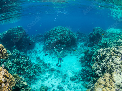 Young man dive at coral reef in tropical sea