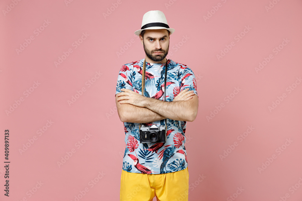 Dissatisfied young traveler tourist man in summer casual clothes hat with photo camera holding hands crossed isolated on pink background. Passenger traveling on weekends. Air flight journey concept. Dissatisfied young traveler tourist man in summer casual clothes hat with photo camera holding hands crossed isolated on pink background. Passenger traveling on weekends. Air flight journey concept.