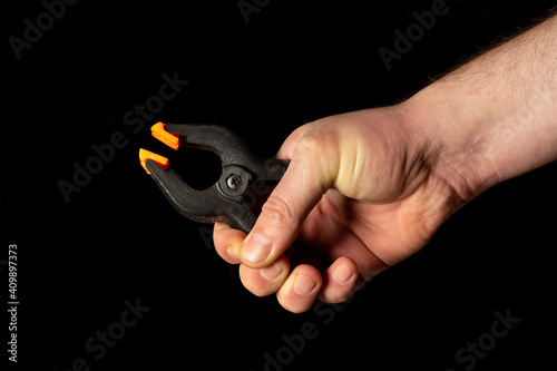 Man hand holds plastic spring clamps on black isolated background