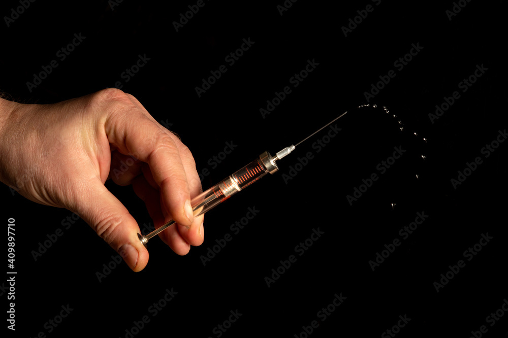 Naklejka premium Medical syringe in man hand on black isolated background closeup