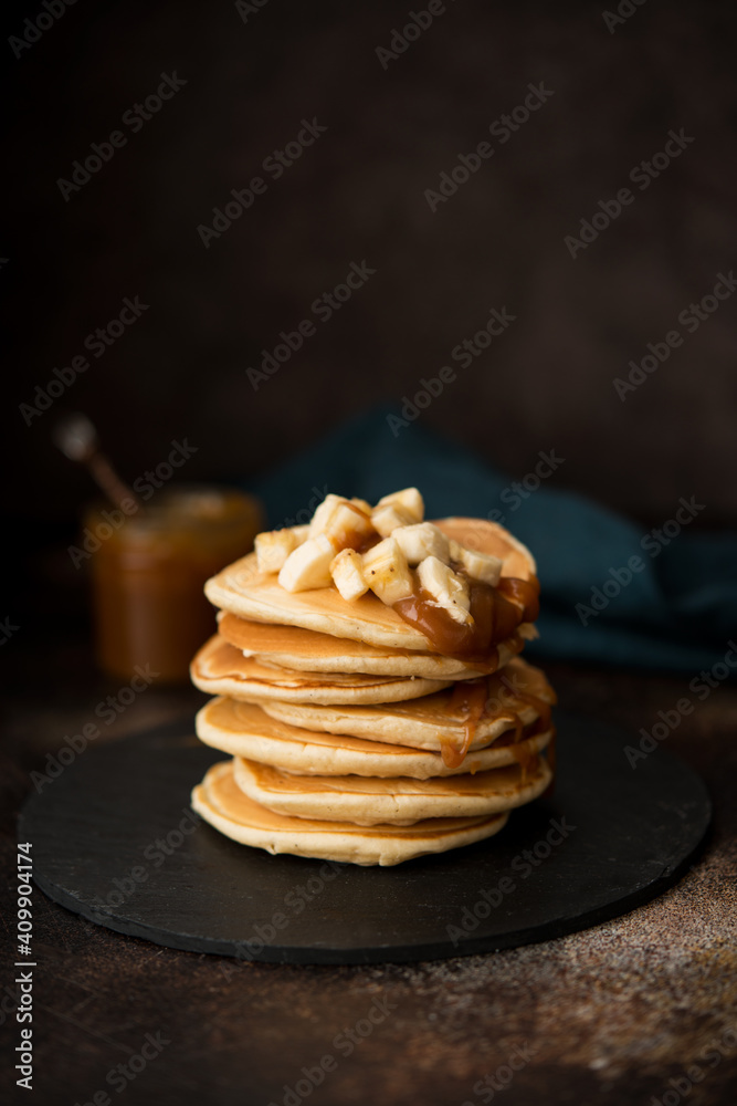 American pancakes with caramel and banana on a dark background American pancakes with caramel and banana on a dark background