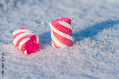 marshmallow lies on a white snow-covered background. Winter Christmas background.
