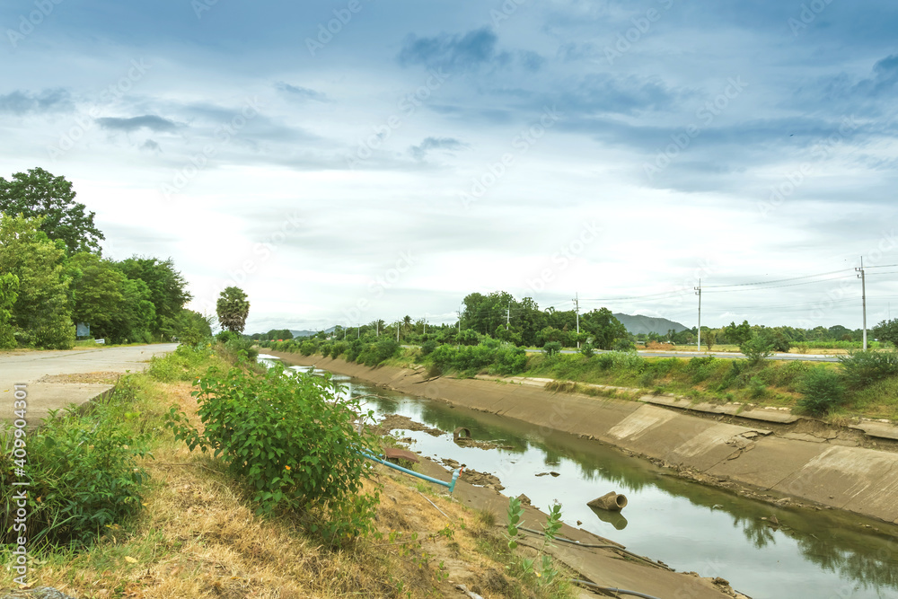 Irrigation canal in concrete wall Send water from the reservoir to the agricultural area of the farmer that is dry in the rainy season of Thailand. Environmental disaster in agriculture. Irrigation canal in concrete wall Send water from the reservoir to the agricultural area of the farmer that is dry in the rainy season of Thailand. Environmental disaster in agriculture.