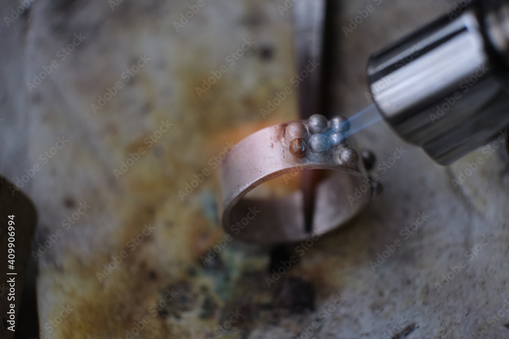Fototapeta premium Macro shot. Craft jewelery making with professional tools. A handmade jeweler process, manufacture of jewellery. Melting metal