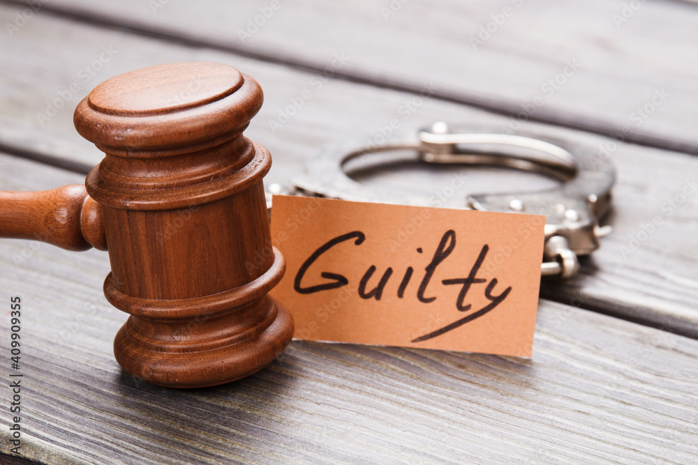 Guilty and crime concept. Close-up brown wooden gavel with handcuffs on wooden desk. Guilty and crime concept. Close-up brown wooden gavel with handcuffs on wooden desk.