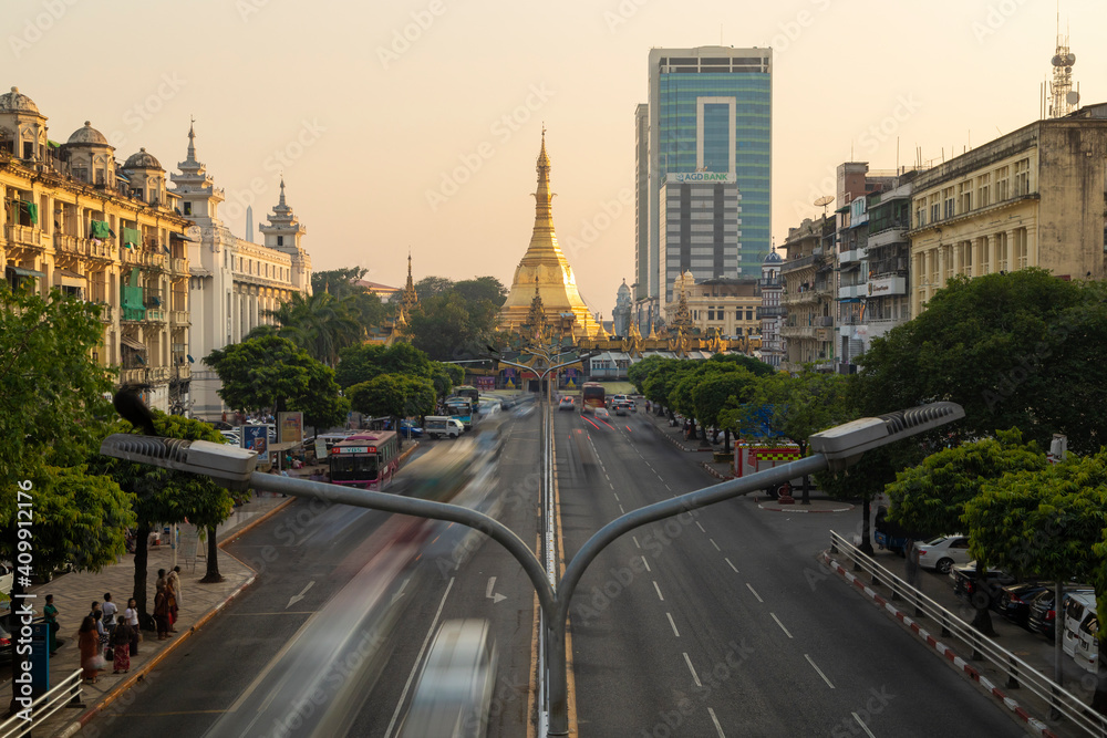 General view of Sule Pagoda Buddhist temple and stupa, decorated in gold, surrounded by traffic, from the Sule Paya Road Pedestrian Bridge, in Downtown Yangon. - obrazy, fototapety, plakaty 