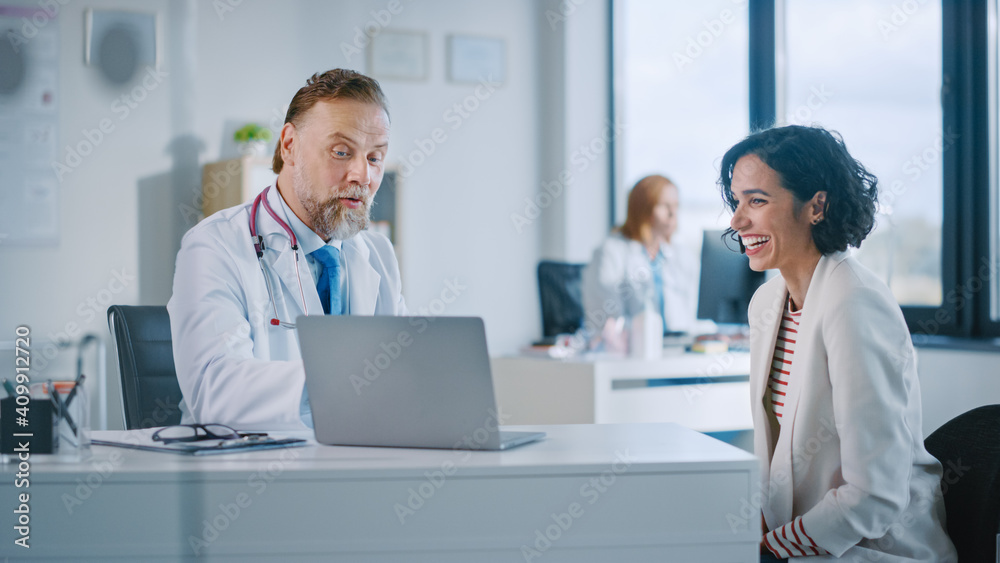 Family Doctor is Delivering Great News About Female Patient's Medical Results During Consultation in a Health Clinic. Physician in White Lab Coat Sitting Behind a Computer in Hospital Office. Family Doctor is Delivering Great News About Female Patient's Medical Results During Consultation in a Health Clinic. Physician in White Lab Coat Sitting Behind a Computer in Hospital Office.