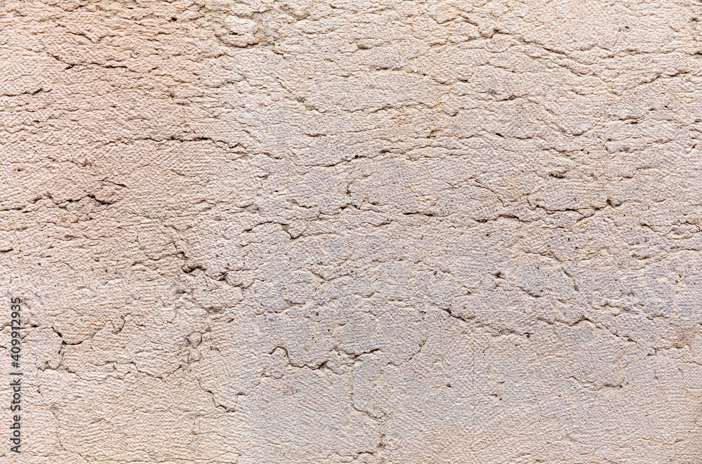 Old beige stucco wall with cracks texture