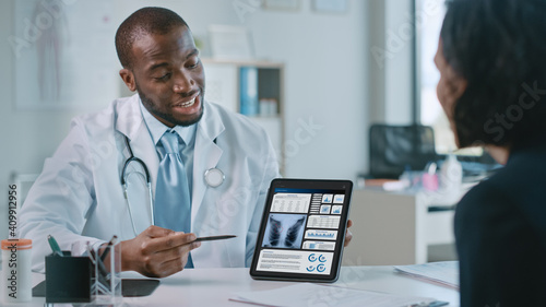 Doctor Consultation Office: Female Patient Listens to Experienced Pulmonologist Uses Digital Tablet Computer to Show, Explain Lung Analysis Results, Give Advice, Prescribe High-Pressure Medicine photo