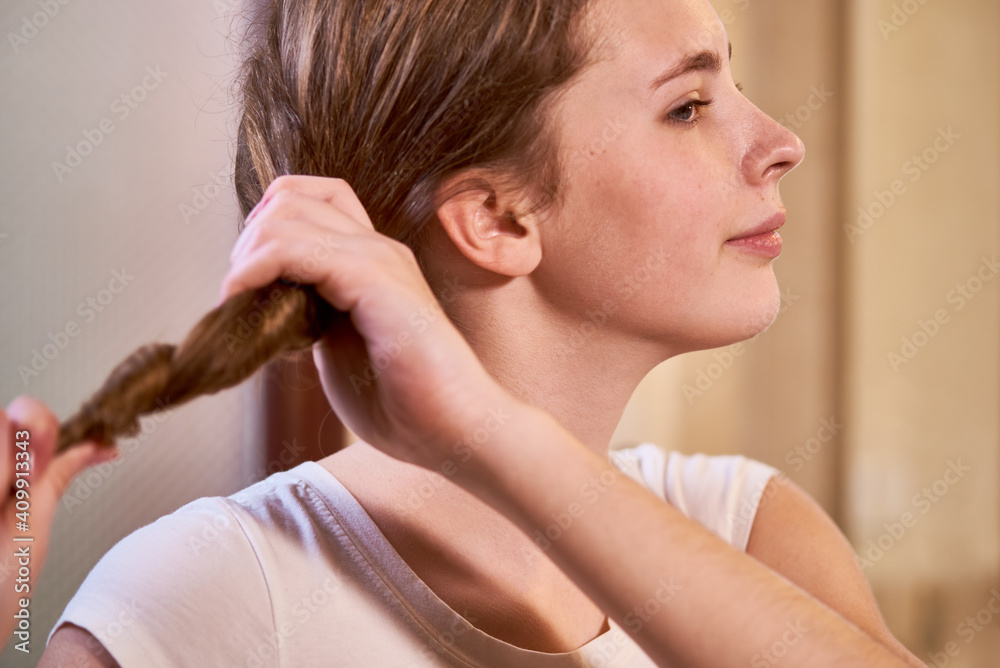 Pretty smiling teenage girl squeezing hair after taking morning shower