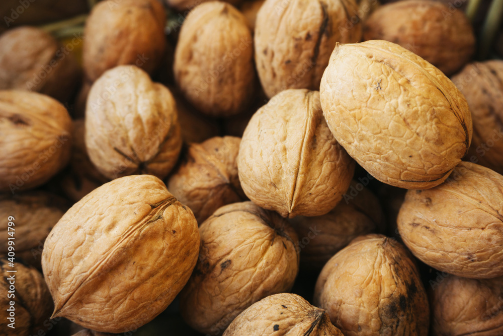 Walnut background. Natural walnuts texture. Nuts in shells. Stacked pile of wallnuts pattern. Walnut background. Natural walnuts texture. Nuts in shells. Stacked pile of wallnuts pattern.