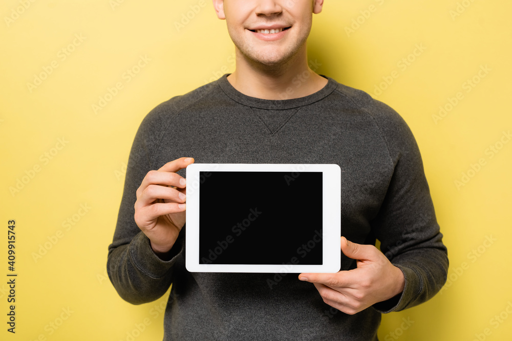 Cropped view of smiling man holding digital tablet on yellow background