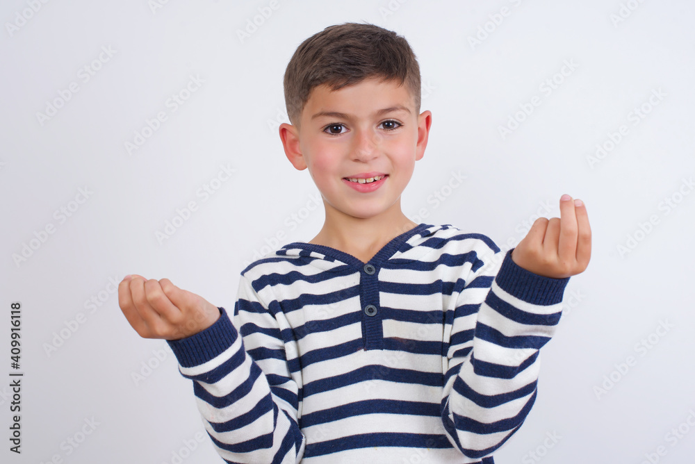 little cute boy kid wearing stripped t-shirt against white wall, making money gesture. little cute boy kid wearing stripped t-shirt against white wall, making money gesture.