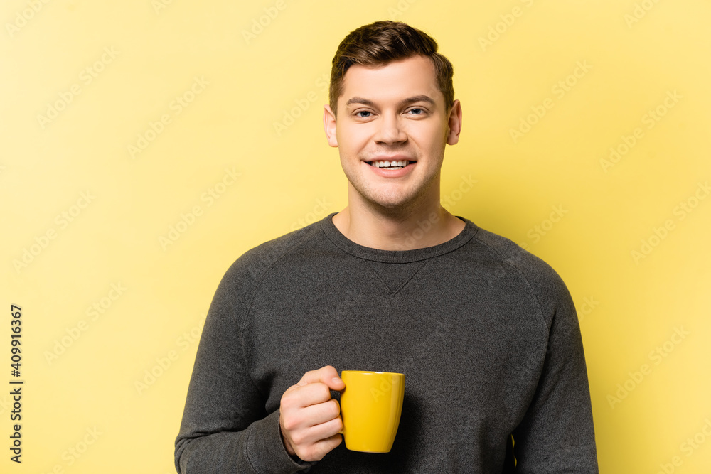 Man holding cup and smiling at camera on yellow background Man holding cup and smiling at camera on yellow background