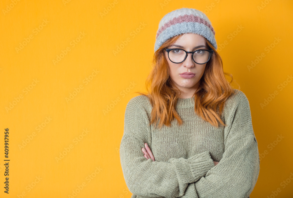 Serious beautiful woman with crossed arms, isolated on yellow background. Cute girl looking in camera