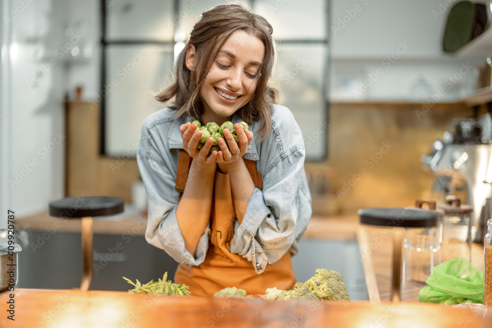 Portrait of pretty woman in apron with fresh brussels sprouts on the kitchen at home. Healthy cooking concept. High quality photo Portrait of pretty woman in apron with fresh brussels sprouts on the kitchen at home. Healthy cooking concept. High quality photo