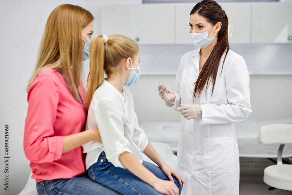female doctor preparing child before making injection, consulting. girl sits with mother in hospital listening to nurse talks female doctor preparing child before making injection, consulting. girl sits with mother in hospital listening to nurse talks