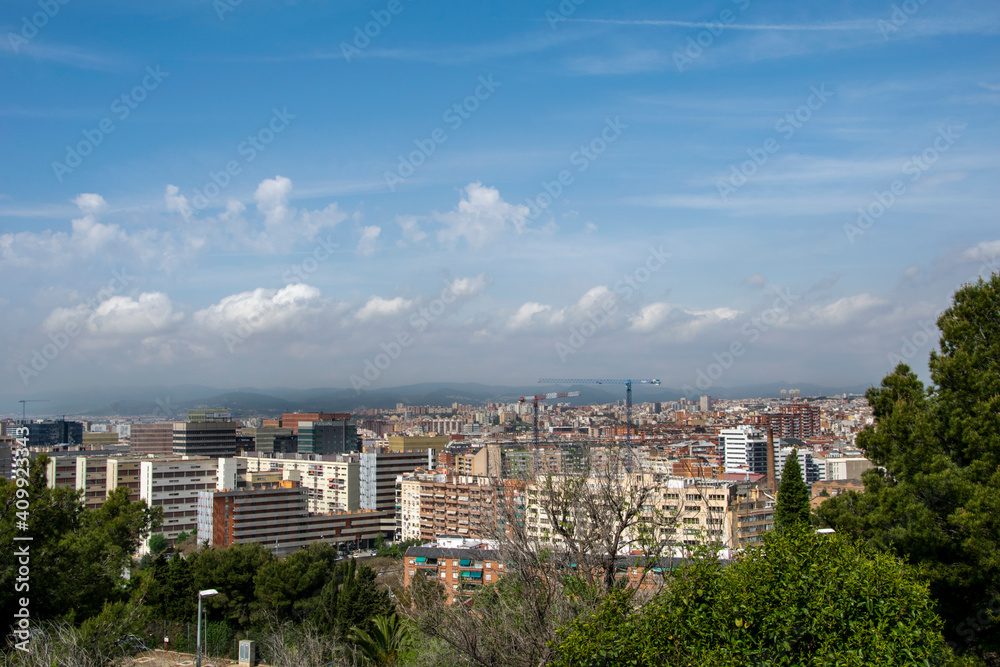 Espacio entre árboles en la montaña de Montjuic desde donde se divisa una parte de Barcelona.