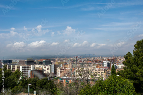 Espacio entre árboles en la montaña de Montjuic desde donde se divisa una parte de Barcelona.