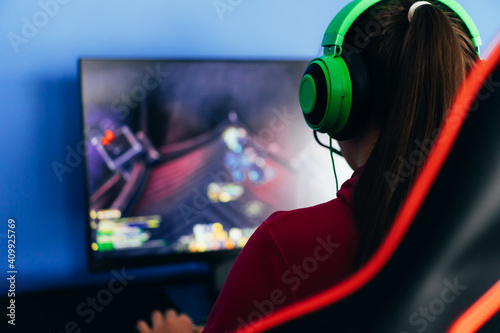 Fényképezés A young girl playing a computer game on professional armchair against monitor in