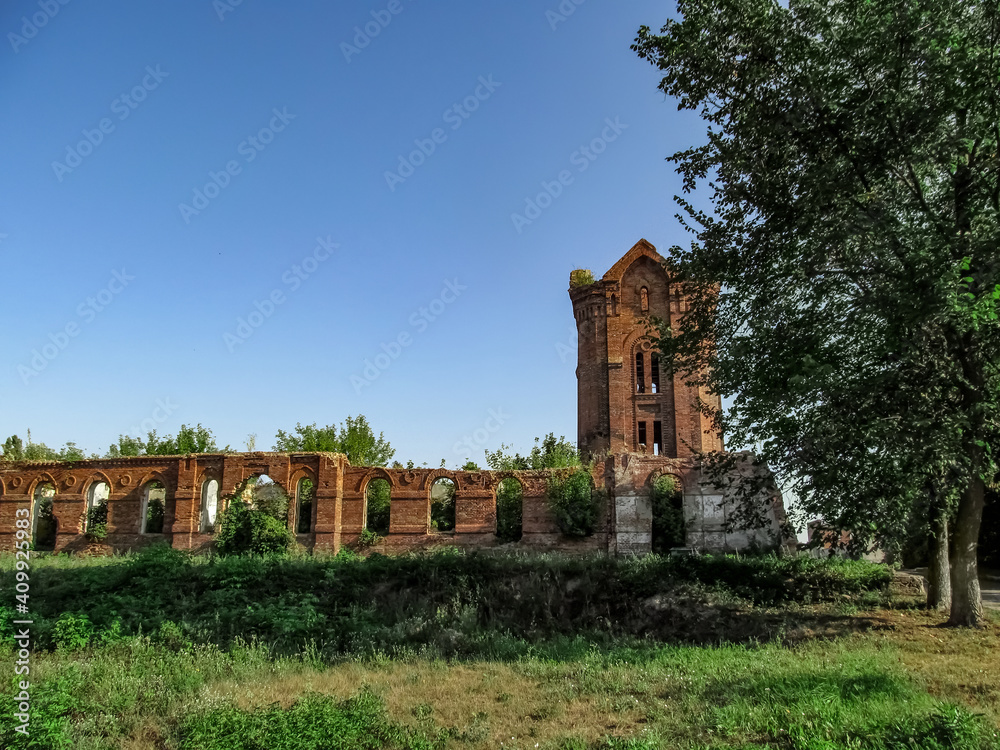 Ruins of the former city baths in Putivl (Sumy region, Ukraine). Remains of an old red brick building with tower in the middle of green nature on a sunny day Ruins of the former city baths in Putivl (Sumy region, Ukraine). Remains of an old red brick building with tower in the middle of green nature on a sunny day