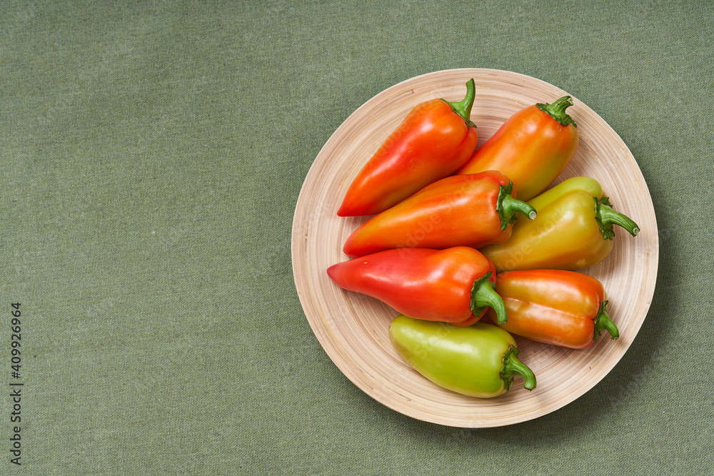 The colored pepper lies horizontal on a wooden plate on a green napkin with text area. The view from the top.