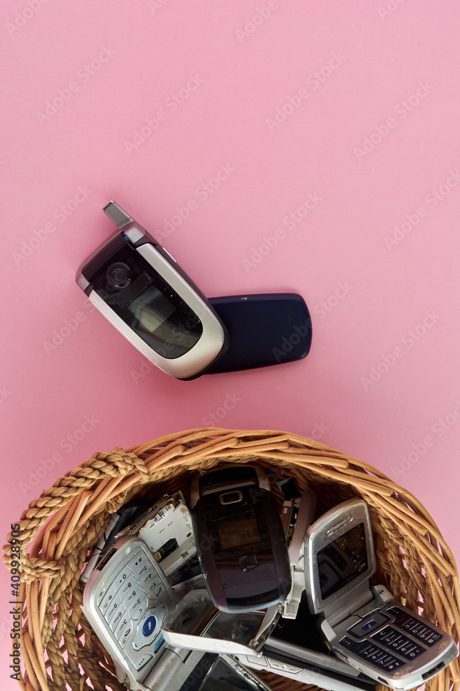 wicker basket, with broken mobile phones, recycling technology, early 2000s  on pink background and copy space Stock Photo | Adobe Stock