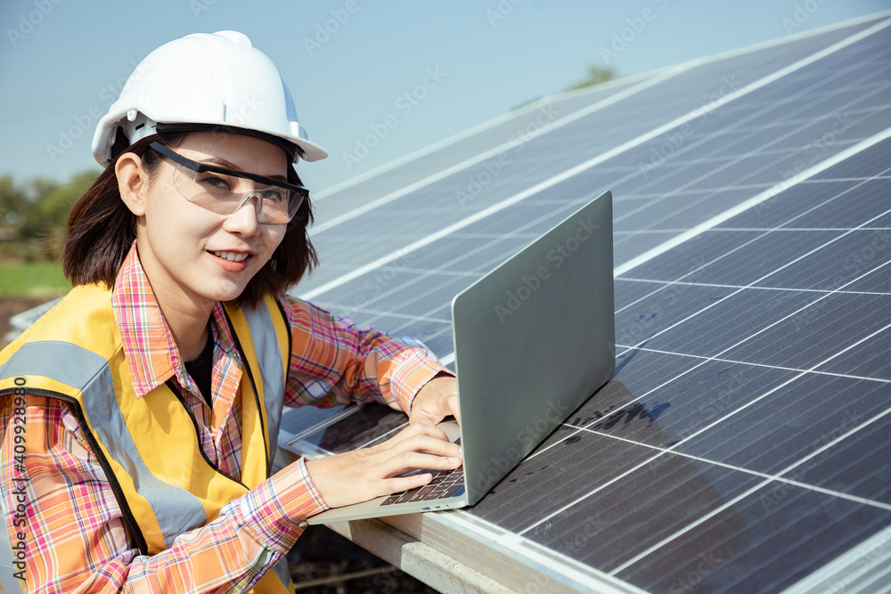 Asian woman workers technicians holding walkie talkies and laptop to control installing heavy solar photo voltaic panels to high steel platform in corn field. Photovoltaic module idea for clean energy Asian woman workers technicians holding walkie talkies and laptop to control installing heavy solar photo voltaic panels to high steel platform in corn field. Photovoltaic module idea for clean energy