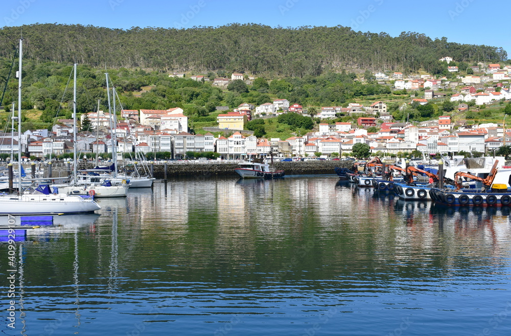 Harbor and coastal village with galician fishing boats and sailing boats at famous Rias Baixas in Galicia Region. 