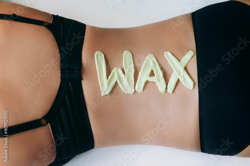 Top view on inscription wax laid out with hot wax for depilation. Hair removal procedure on female back. The concept of depilation, epilation, waxing, shugaring.