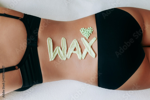 Top view on inscription wax laid out with hot wax for depilation. Heart which composed of granules of depilatory wax. Hair removal procedure on female back.