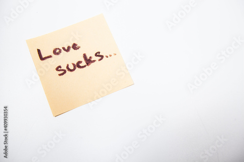 Love sucks written on yellow piece of paper, isolated