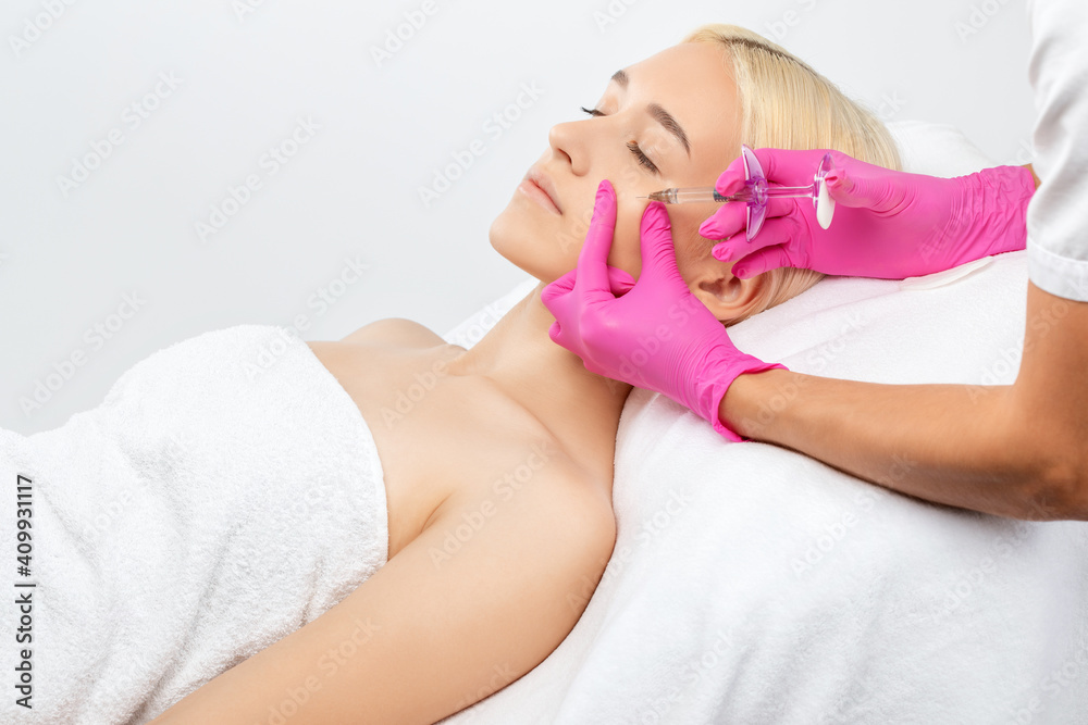 Cosmetologist makes rejuvenating anti wrinkle injections on the face of a beautiful woman. Female aesthetic cosmetology in a beauty salon. Cosmetologist makes rejuvenating anti wrinkle injections on the face of a beautiful woman. Female aesthetic cosmetology in a beauty salon.