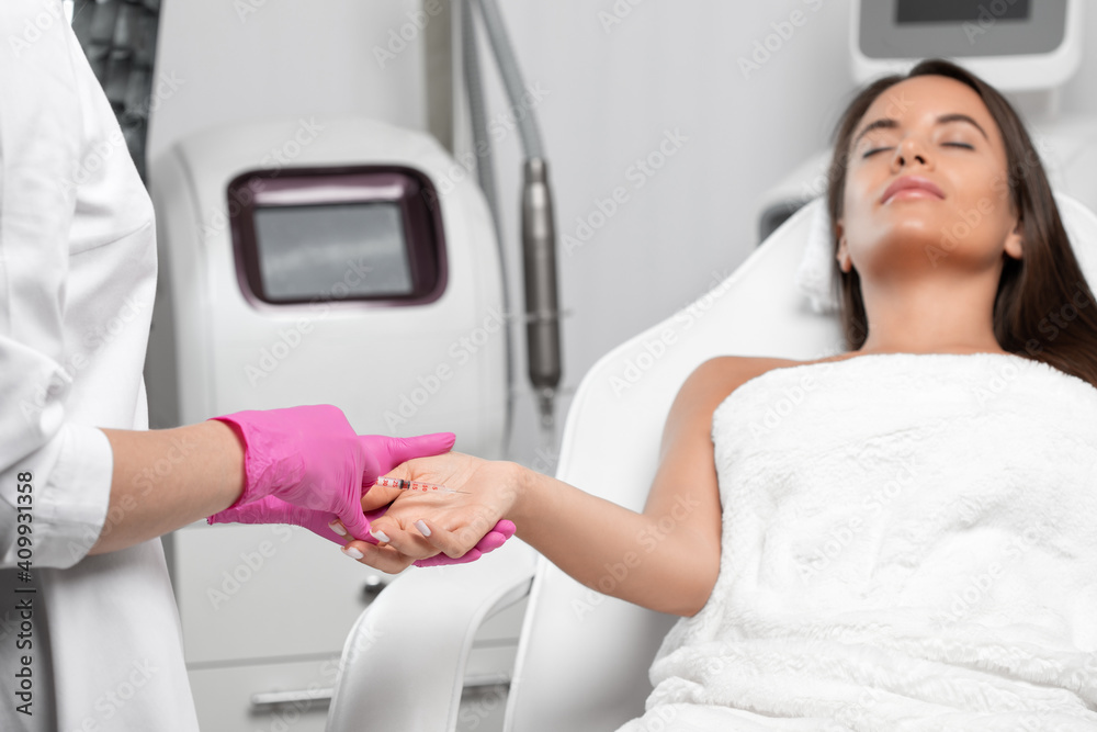 The cosmetologist makes injections of botulinum toxin on the palms of a woman against hyperhidrosis. Women's cosmetology, skin care. The cosmetologist makes injections of botulinum toxin on the palms of a woman against hyperhidrosis. Women's cosmetology, skin care.