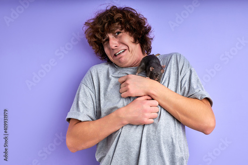 playful rat keep on the alert the man, curly caucasian guy stand can't move, decorative rat is crawling on his t-shirt photo