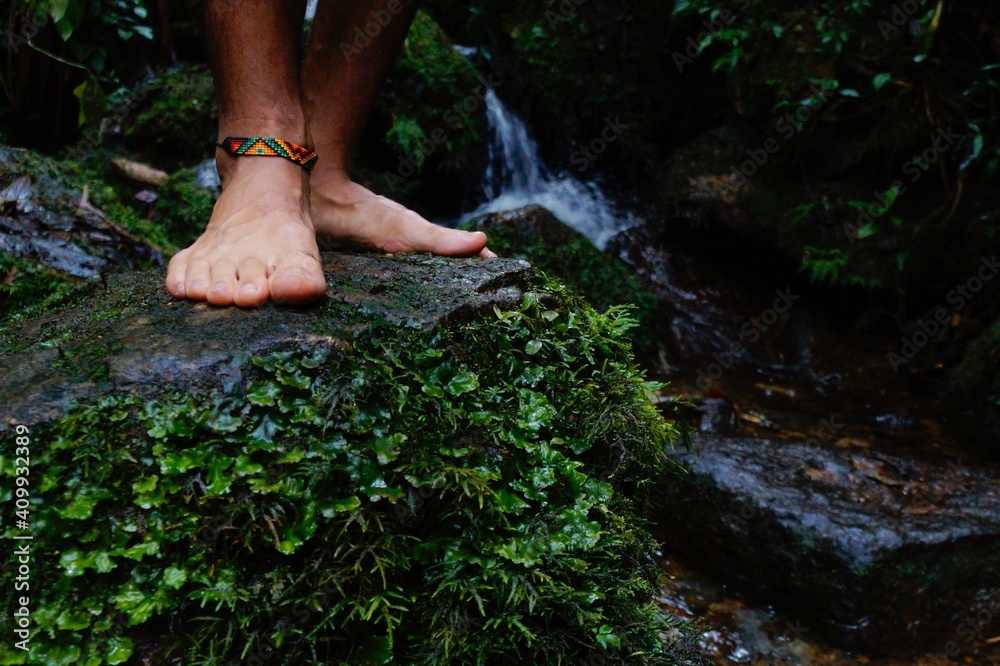 Feet without shoes and with indigenous bracelet on stone in the river Feet without shoes and with indigenous bracelet on stone in the river