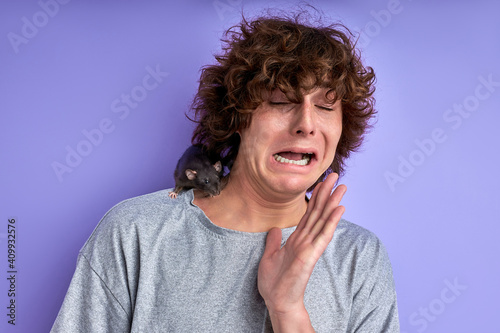 funny man at a loss, does not know what to do with a rat on his t-shirt, grimace, make face photo