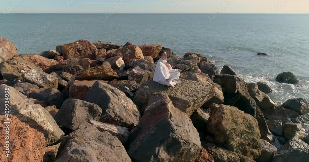 Meditación saludable de mujer de blanco frente al sol y dron orbitando