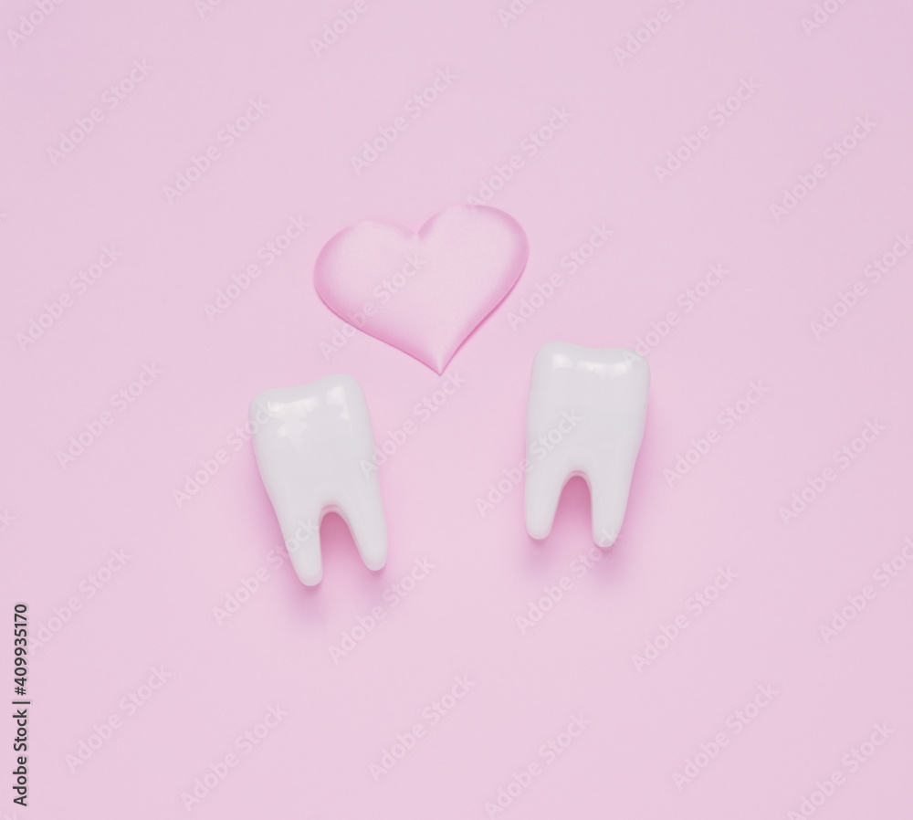 Top view flat lay Two teeth pink hearts pink pastel background. Oral care and St. Valentine's day concept.