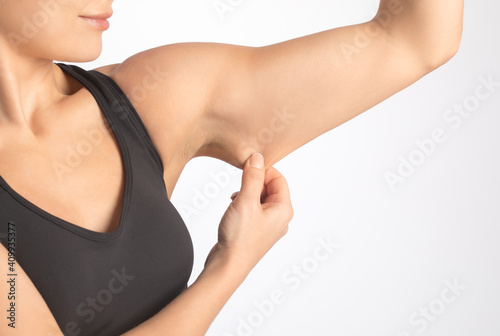A slender woman shows saggy skin on her arm. The concept of proper nutrition and healthy lifestyle.