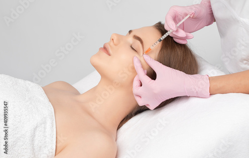 Cosmetologist makes rejuvenating anti wrinkle injections on the face of a beautiful woman. Female aesthetic cosmetology in a beauty salon. © Dimid