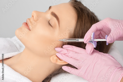 Cosmetologist makes rejuvenating anti wrinkle injections on the face of a beautiful woman. Female aesthetic cosmetology in a beauty salon.