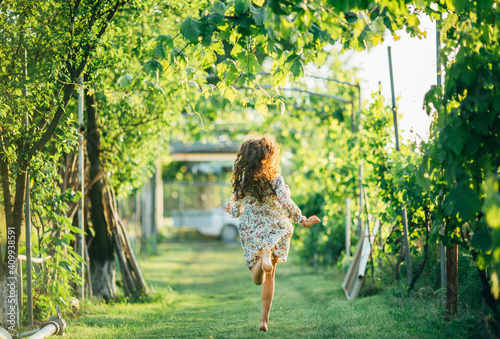 girl runs barefoot on green grass in the garden